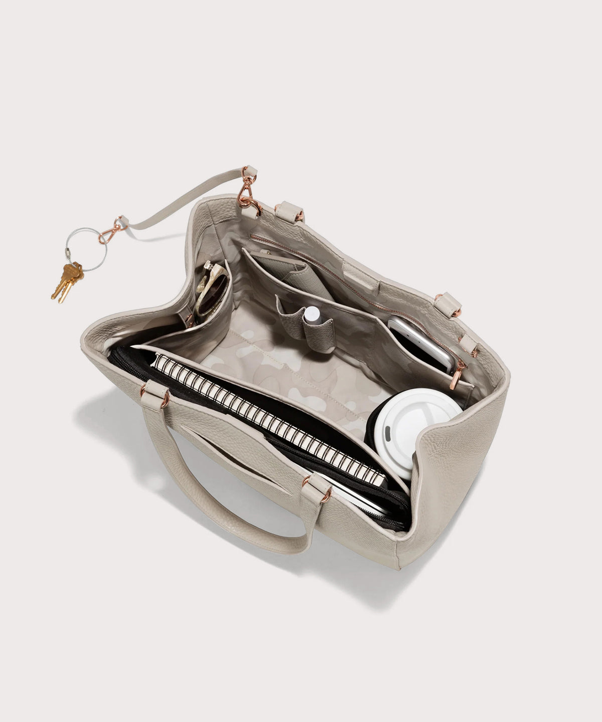hover - Dagne Dover medium Allyn Tote in light grey with objects inside the interior pockets.
