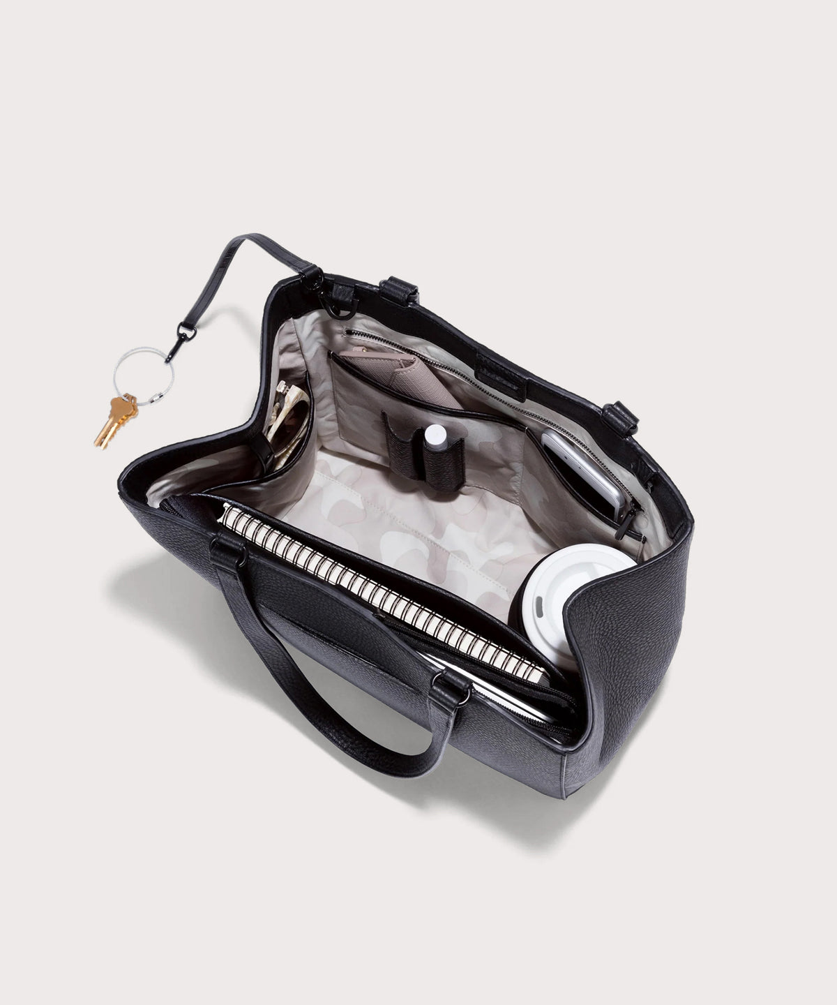 hover - Dagne Dover medium Allyn Tote in black with objects inside the interior pockets.
