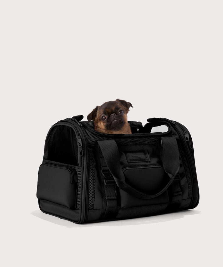 Dagne Dover Small Kyoto Pet Carrier in black seen from an angle with a dog inside the carrier. Caption: Edna is a 5-lb Brussels Griffon. 
