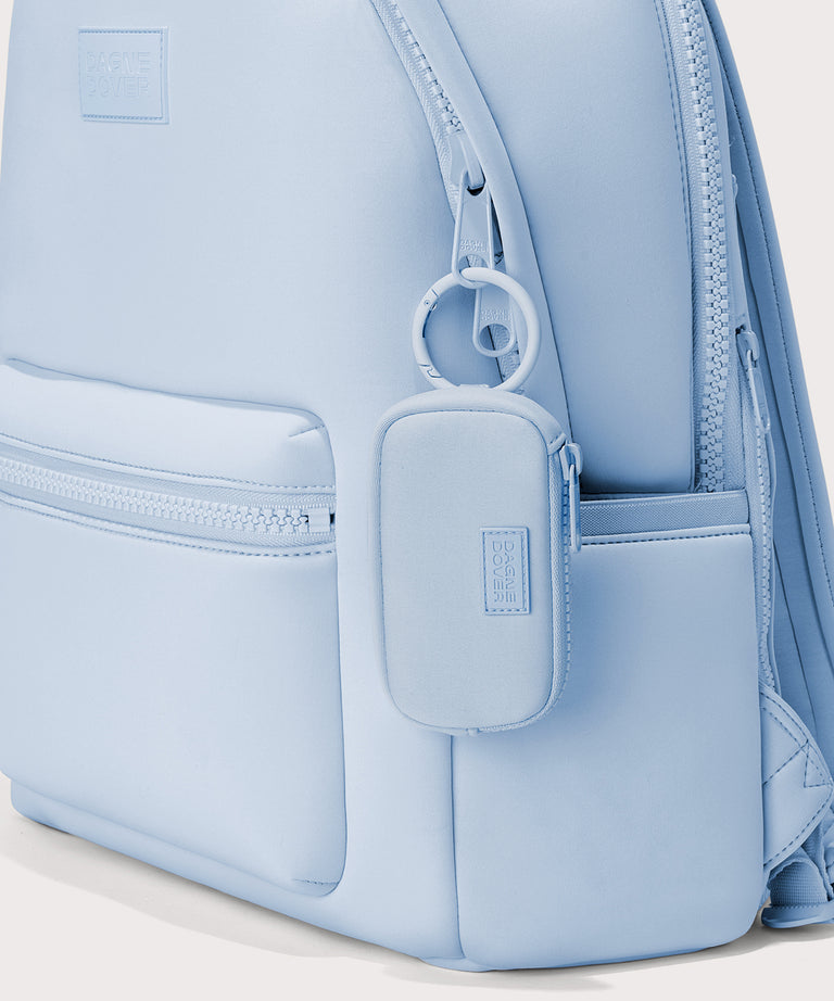 Dagne Dover Mara Keychain in an airy, lighter sky blue clipped onto a backpack. 