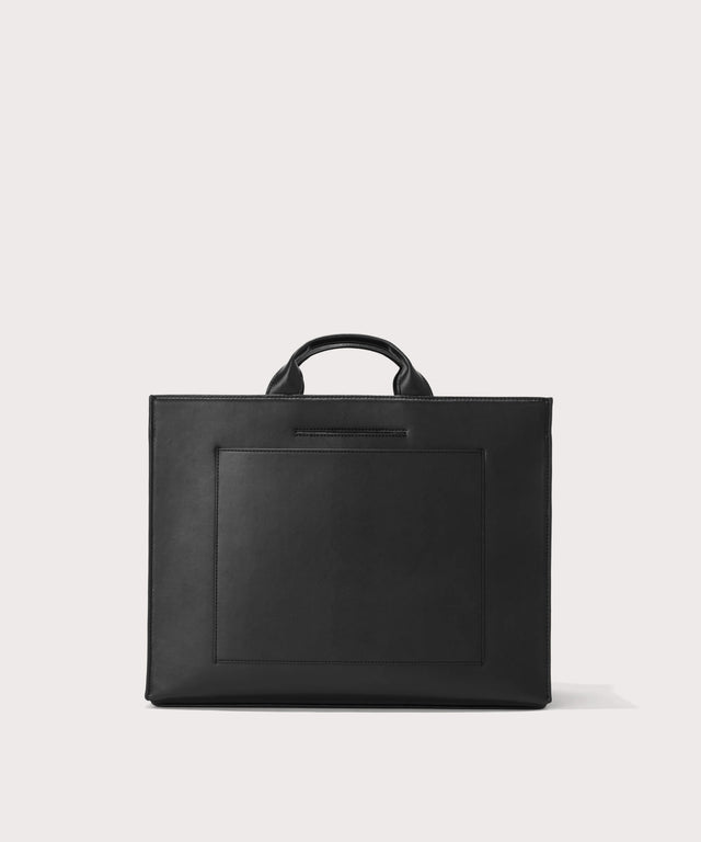 Dagne Dover large vegan Daily Tote in black revealing the exterior phone pocket and exterior luggage sleeve.
