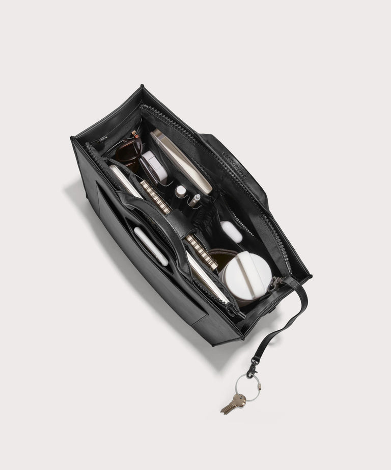 hover - Dagne Dover medium vegan Daily Tote in black from above, revealing the interior zipper, interior slip pockets, and padded laptop sleeve.
