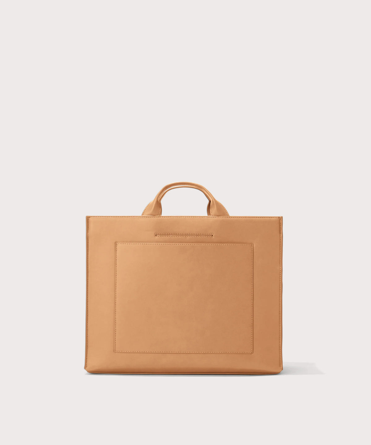 Dagne Dover medium vegan Daily Tote in brown revealing the exterior phone pocket and exterior luggage sleeve.
