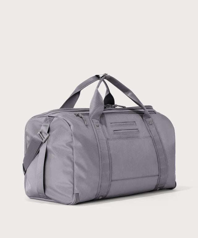 3/4 back view of Monaco garment duffle in a light grey showing back zippered tech pocket and phone/passport pockets

