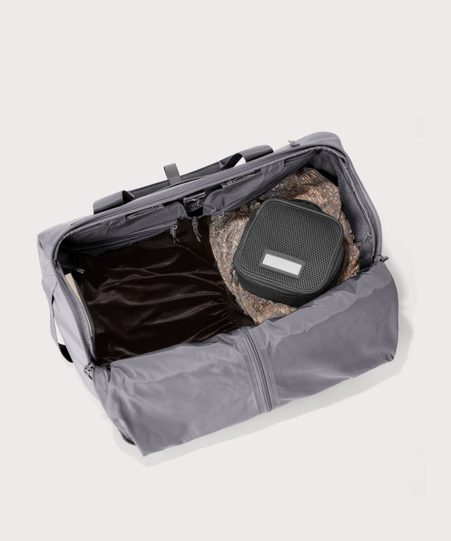Top down of Monaco garment duffle in a light grey with packing cube on the right side.
