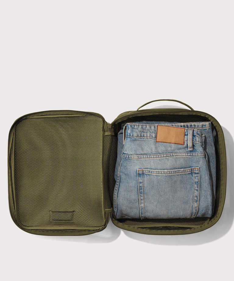 Large Roma packing cube in dark green open with jeans inside
