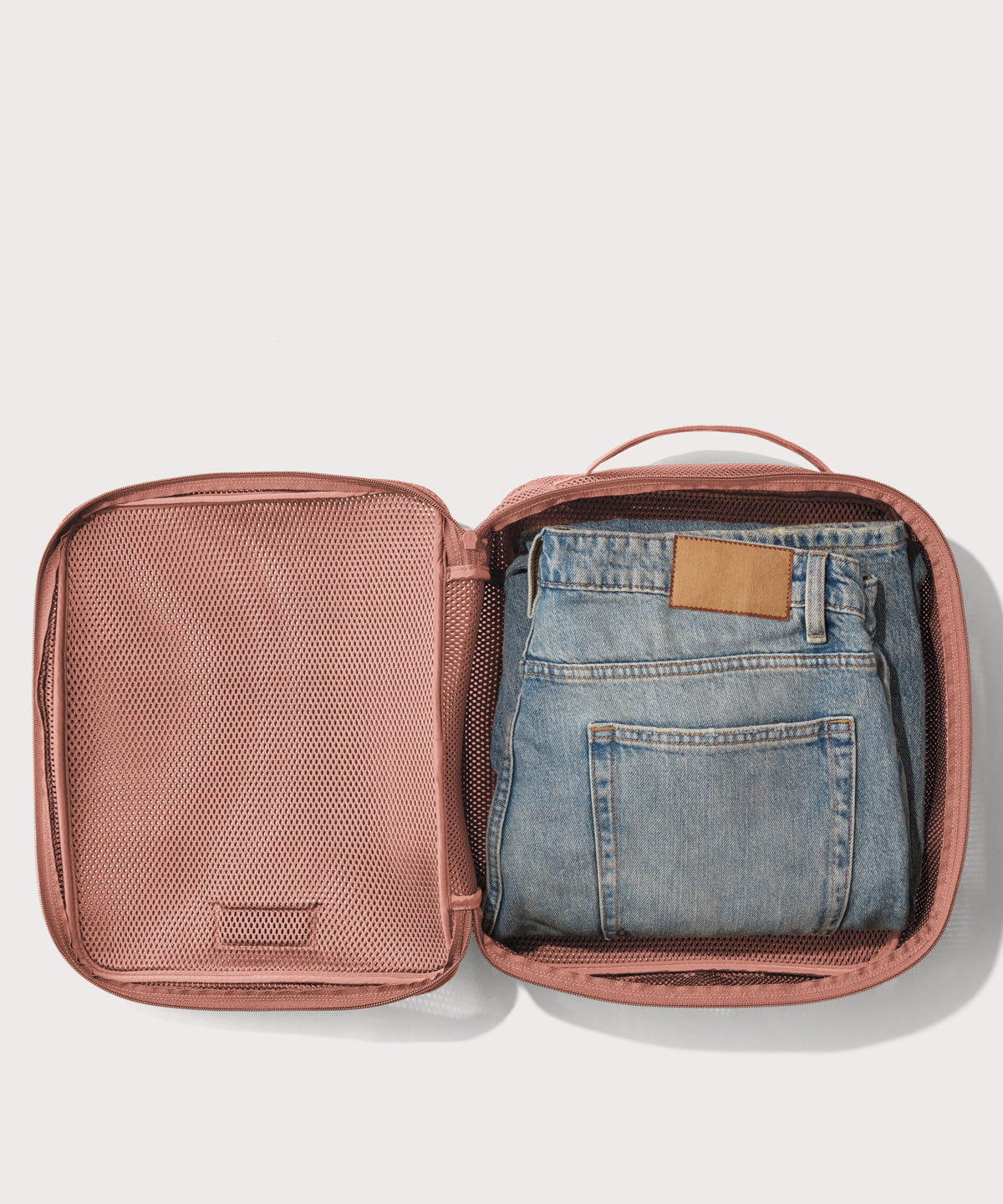 Large Roma packing cube in warm dust pink open with jeans inside