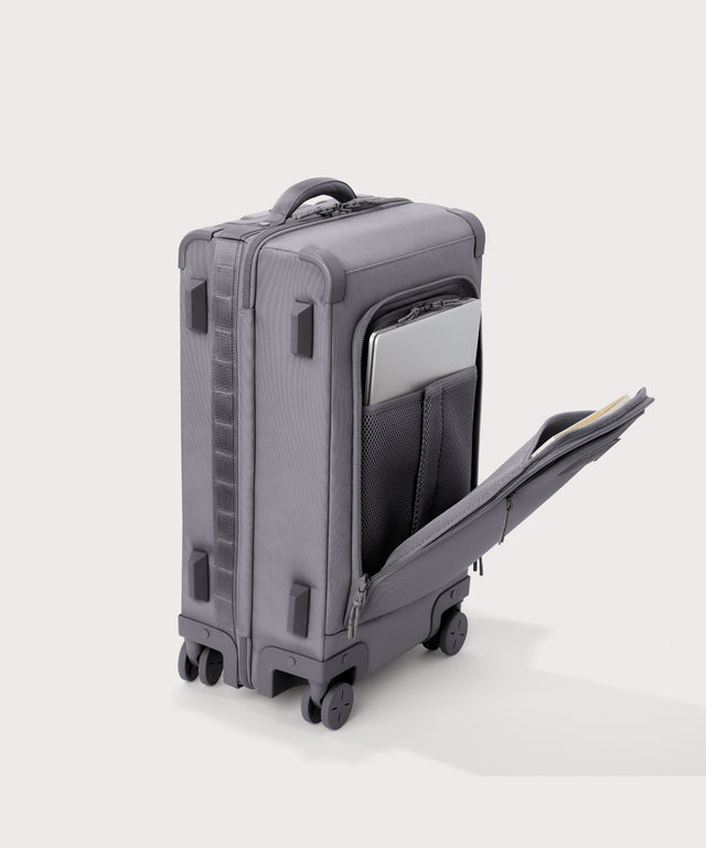 ¾ front view of Seattle carry-on rolling luggage 23.5” in light grey with front flap opened. Caption: Interior slip pocket fits most 16