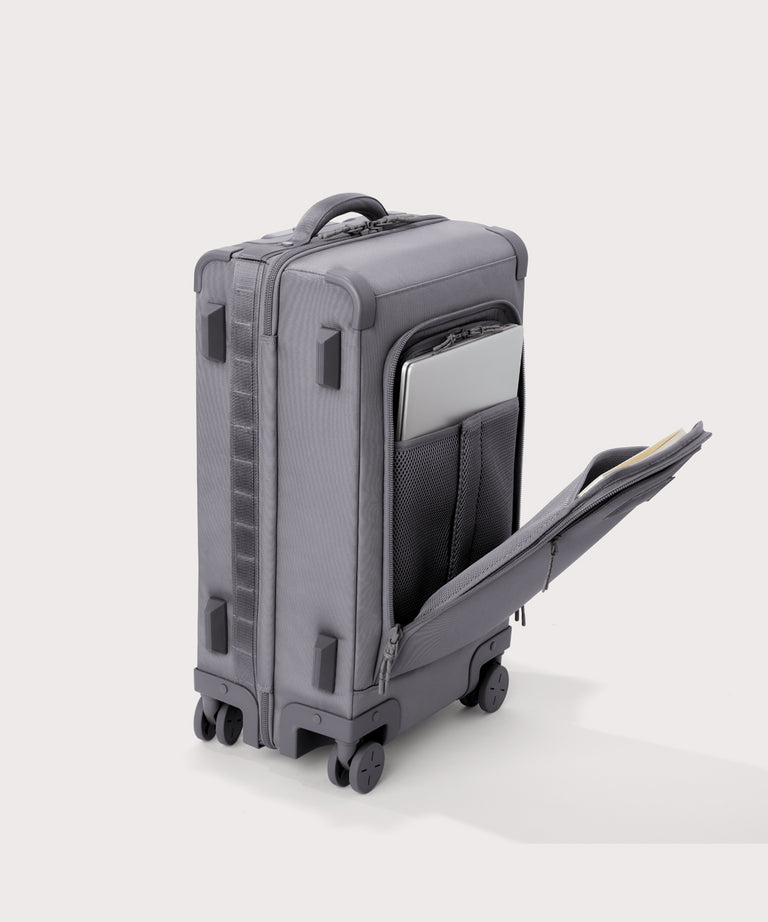 ¾ front view of Seattle carry-on rolling luggage 23.5” in light grey with front flap opened. Caption: Interior slip pocket fits most 16" laptops
