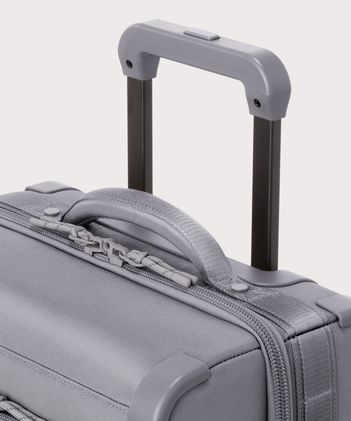 Detail shot of Seattle carry-on rolling luggage 23.5” in light grey extended luggage handle and puffy handle
