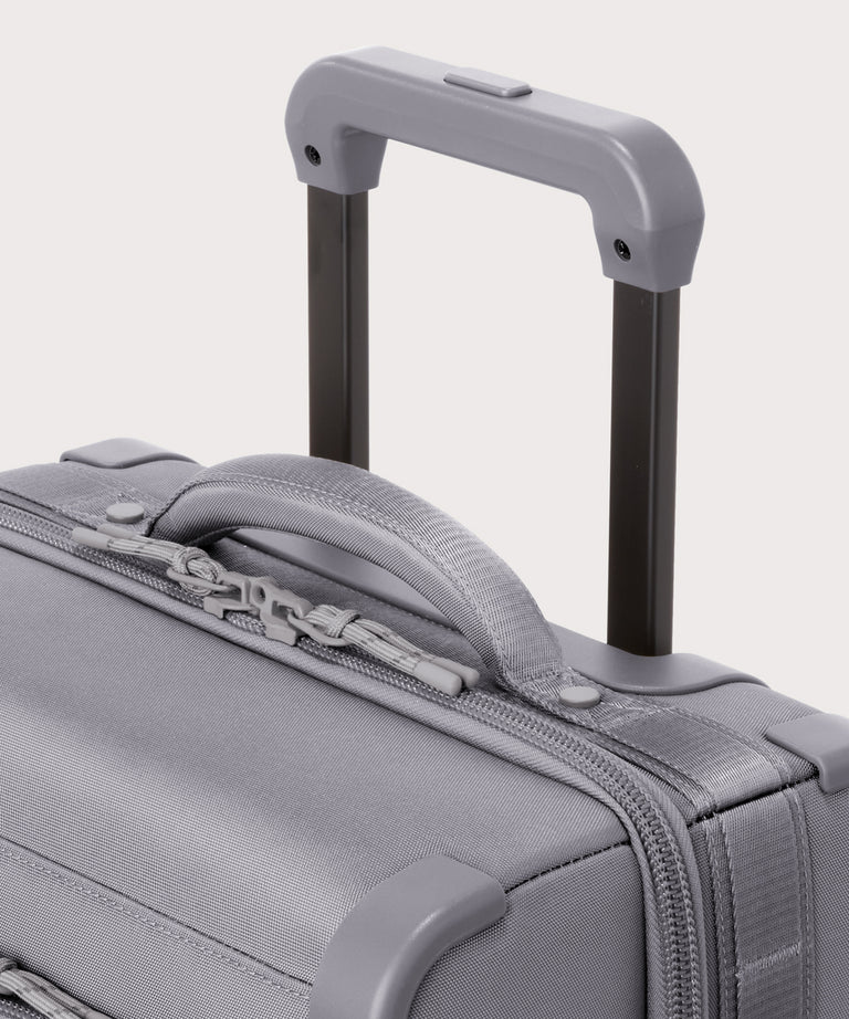 Detail shot of Seattle carry-on rolling luggage 20.5” in light grey extended luggage handle and puffy handle
