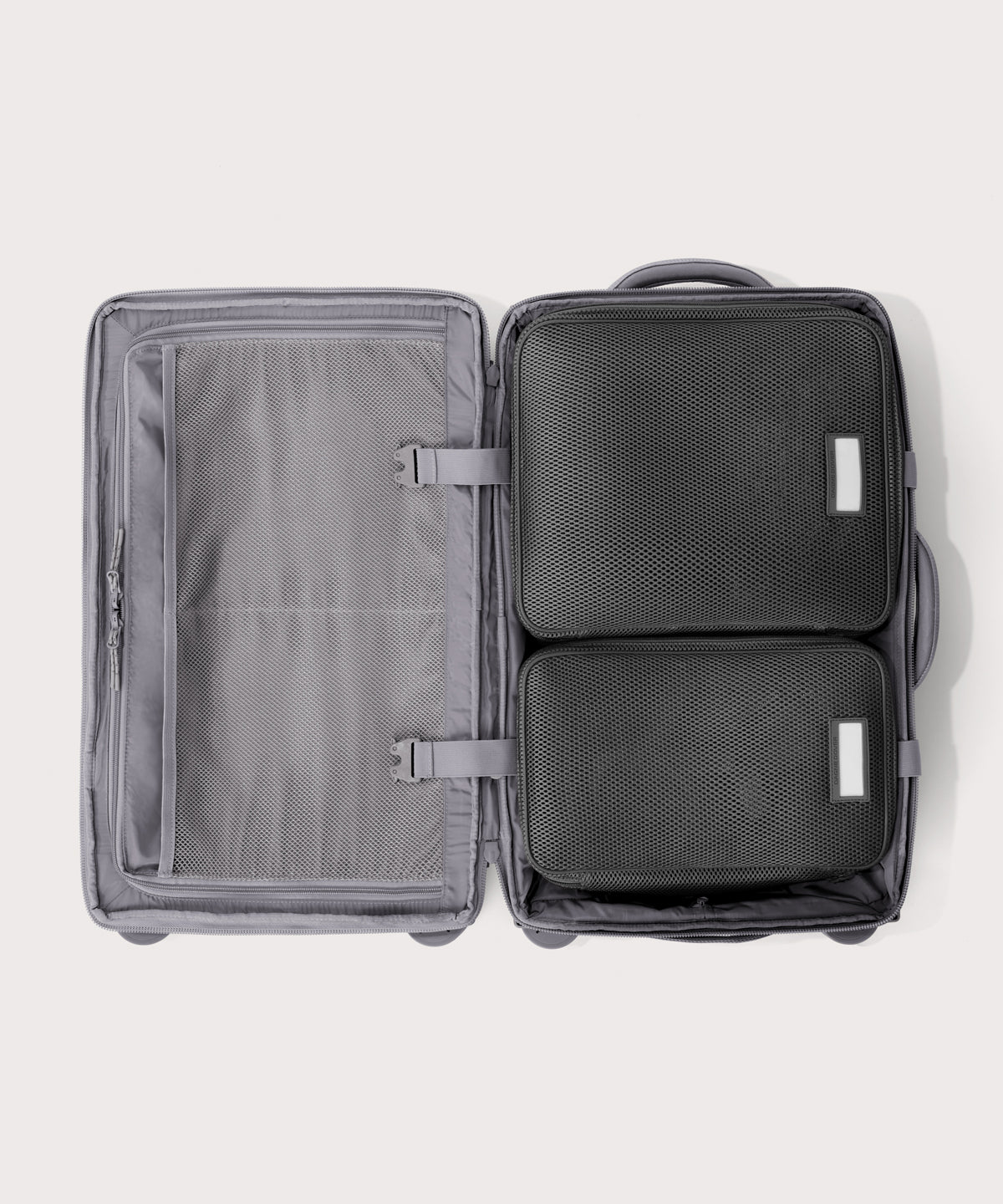 Top down of Seattle carry-on rolling luggage 23.5” in light grey with interior divider zipped and packing cubes packed into the right side.
