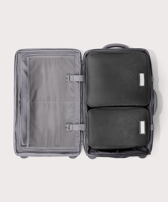 Top down of Seattle carry-on rolling luggage 23.5” in light grey with interior divider zipped and packing cubes packed into the right side.
