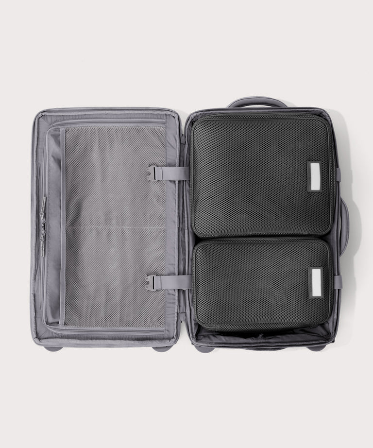 Top down of Seattle carry-on rolling luggage 23.5” in light grey with interior divider zipped and packing cubes packed into the right side.

