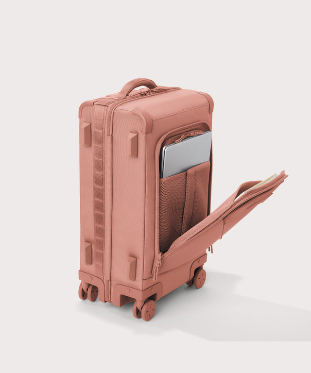 ¾ front view of Seattle carry-on rolling luggage 23.5” in warm dust pink with front flap opened. Caption: Interior slip pocket fits most 16