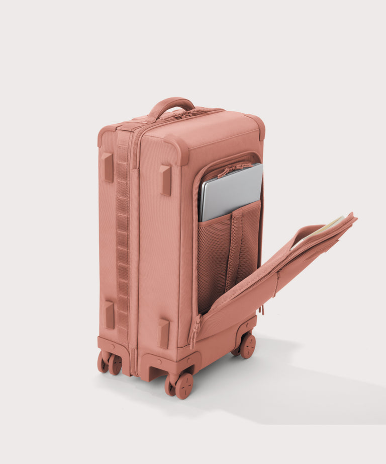 ¾ front view of Seattle carry-on rolling luggage 23.5” in warm dust pink with front flap opened. Caption: Interior slip pocket fits most 16" laptops
