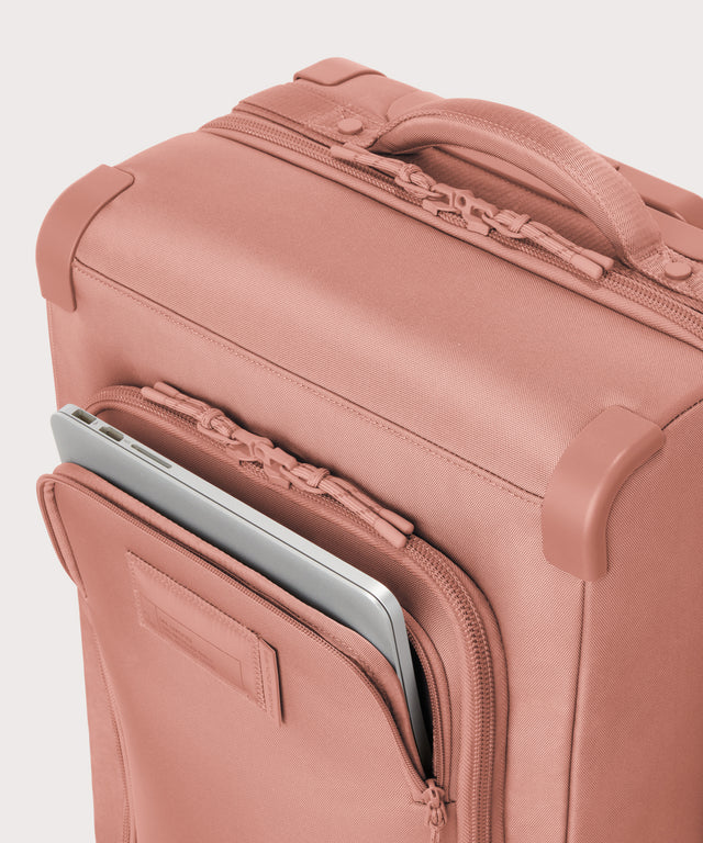 Top down of Seattle carry-on rolling luggage 23.5” in warm dust pink with front flap opened. 

