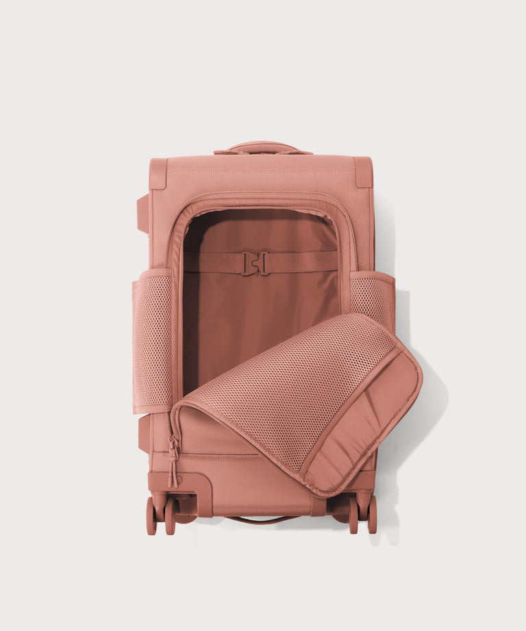 Top down of Seattle carry-on rolling luggage 23.5” in warm dust pink with front flap opened. 
