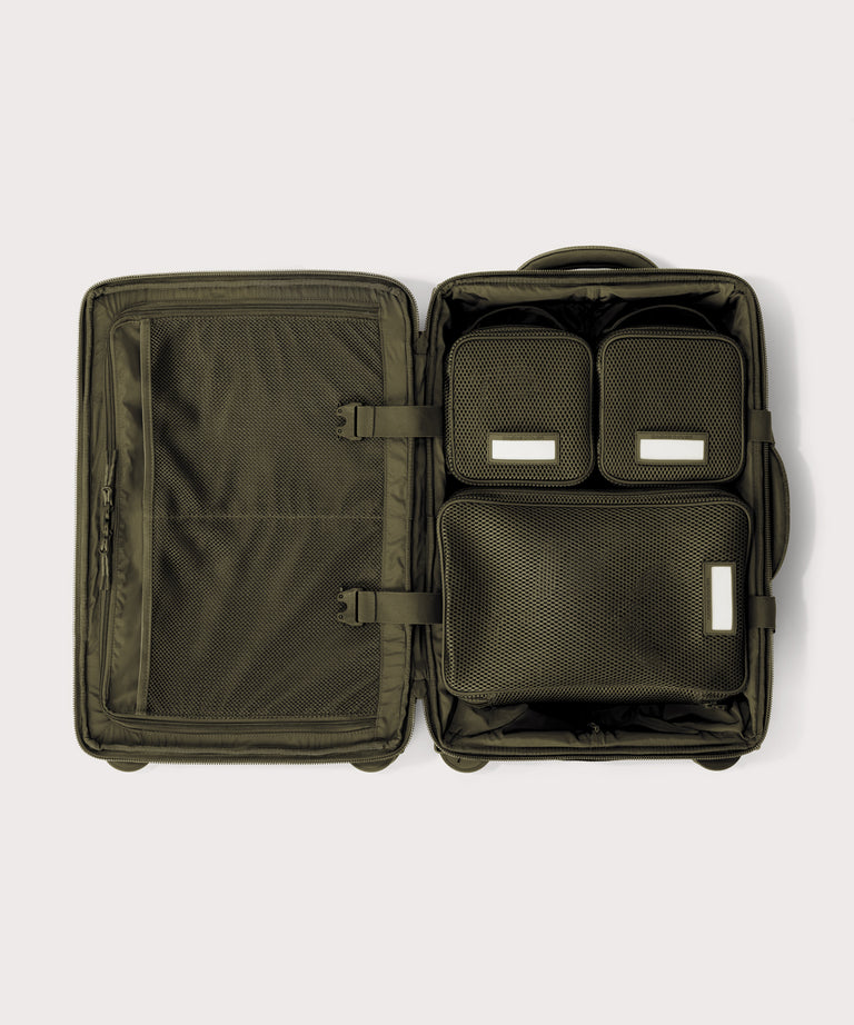 Top down of Seattle carry-on rolling luggage 20.5” in dark green with interior divider zipped and packing cubes packed into the right side. 
