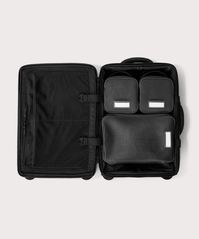 Top down of Seattle carry-on rolling luggage 20.5” in onyx with interior divider zipped and packing cubes packed into the right side. 
