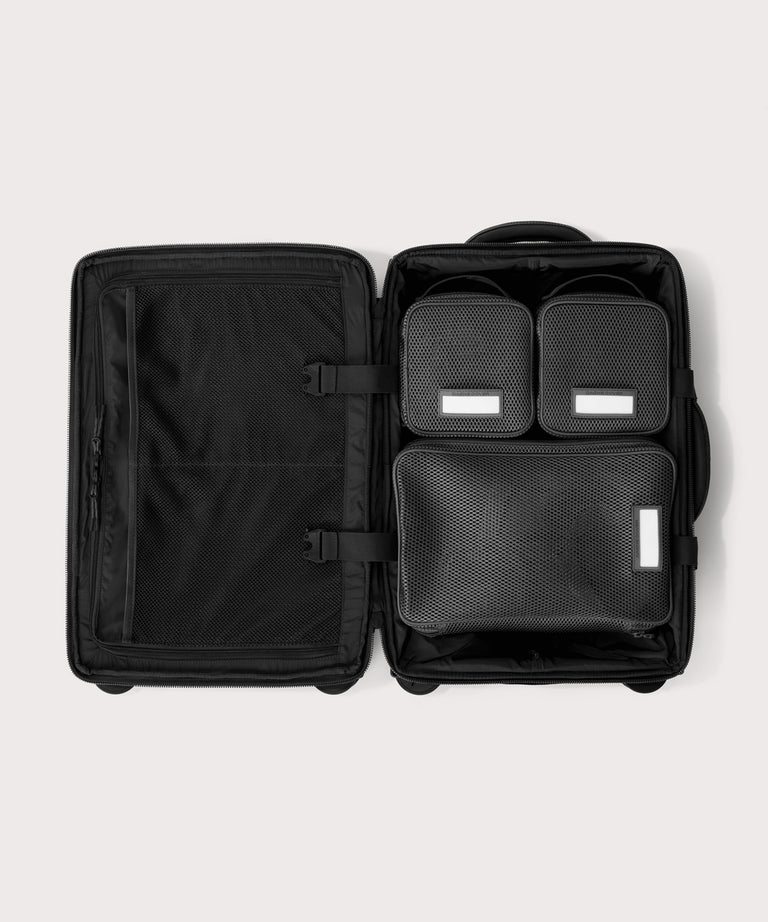 Top down of Seattle carry-on rolling luggage 20.5” in onyx with interior divider zipped and packing cubes packed into the right side. 
