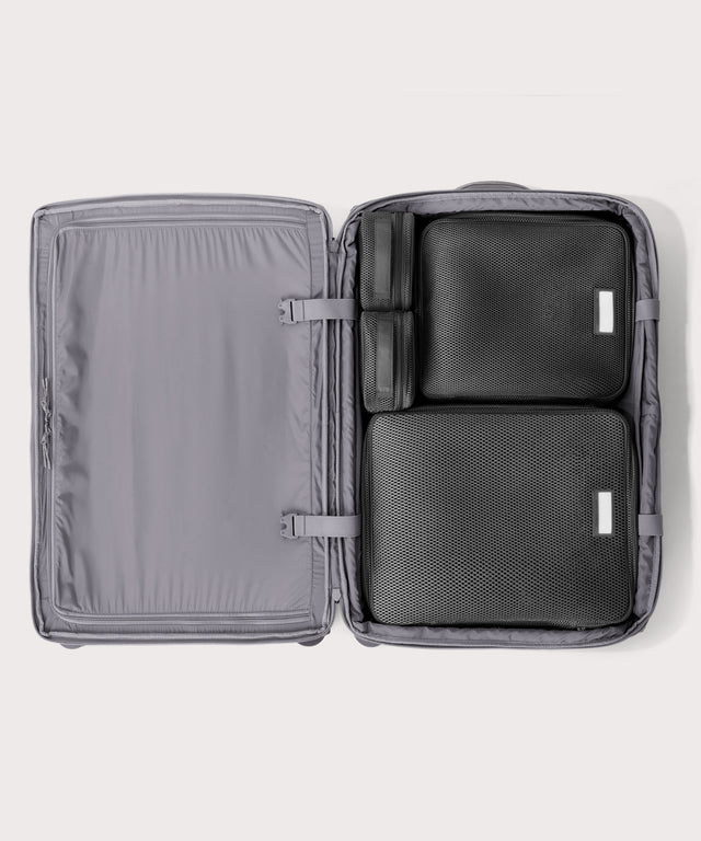 Top down of Sydney checked rolling luggage 28.5” in light grey with interior divider zipped and packing cubes packed into the right side. 
