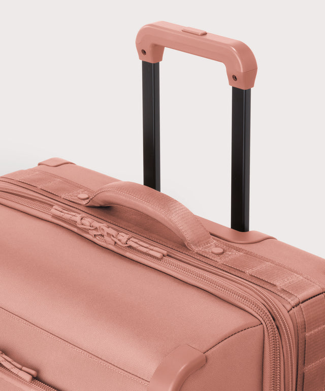 Detail shot of Sydney checked rolling luggage 28.5” in warm dust pink extended luggage handle and puffy handle