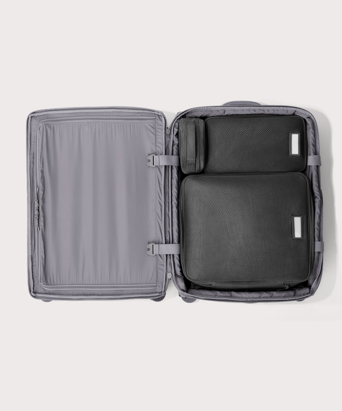 Top down of Sydney checked rolling luggage 25" in light grey with interior divider zipped and packing cubes packed into the right side. 
