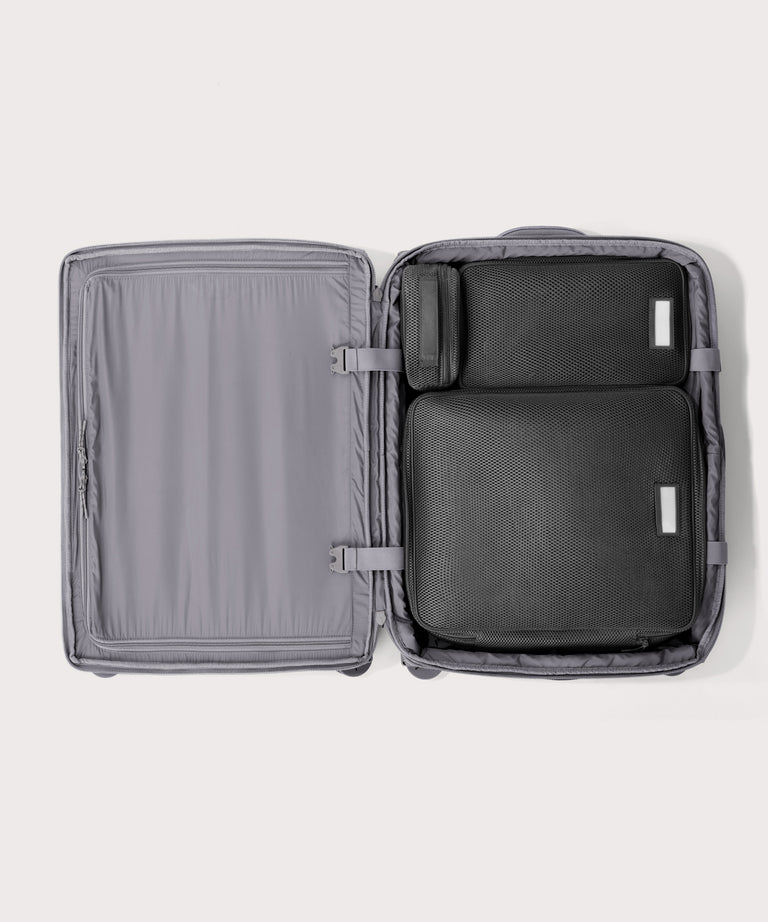 Top down of Sydney checked rolling luggage 25" in light grey with interior divider zipped and packing cubes packed into the right side. 
